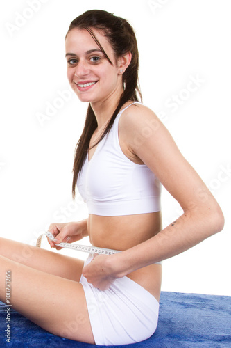 Smiling woman measuring her perfect shape of beautiful thigh waist.