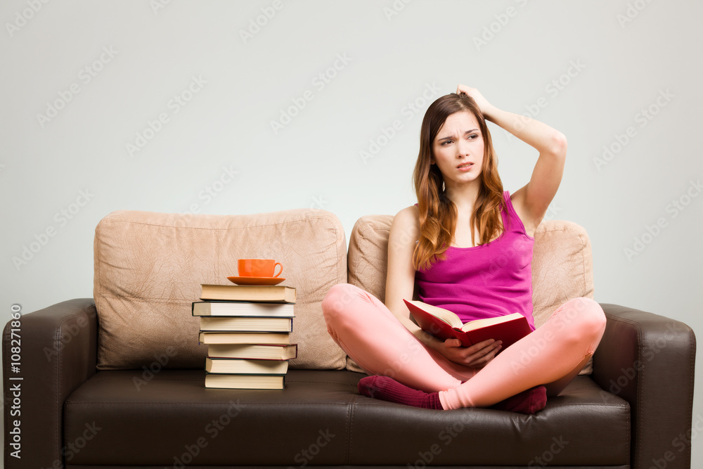 Young woman reading a book while sitting on the couch. Young woman reading a book while sitting on the couch.