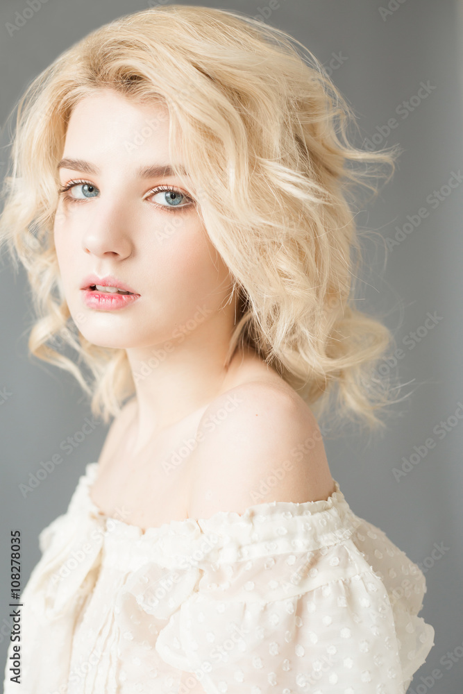 Woman with white hair in a white blouse with nude makeup on a gray background Woman with white hair in a white blouse with nude makeup on a gray background