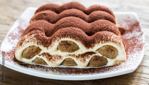 Tiramisu on the plate on the wooden background