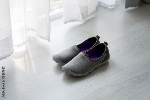 Gray, purple fabric shoes beside view for walking on wooden gra