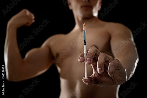 young athletic sportsman holding syringe in sport doping and cheat concept photo