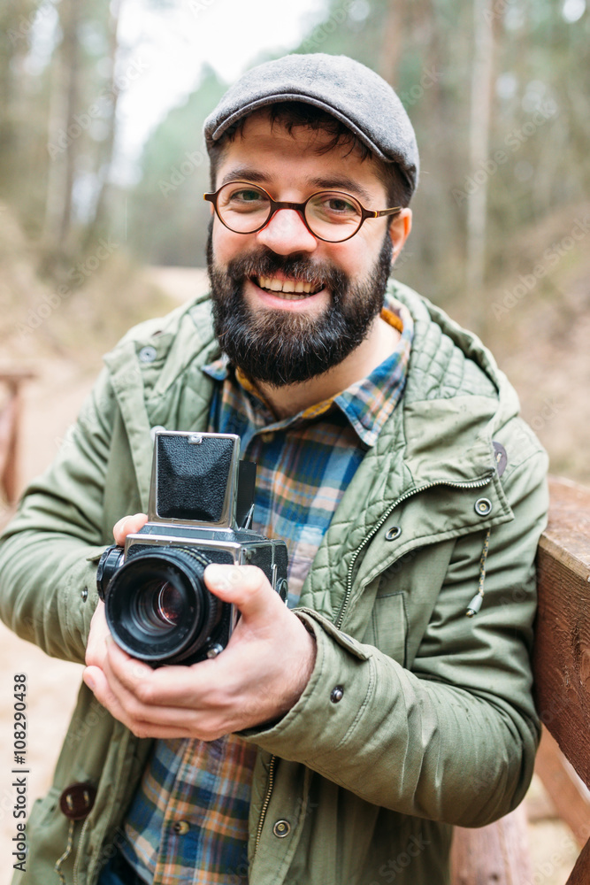 Obraz premium Young man bearded with film photocamera in the forest