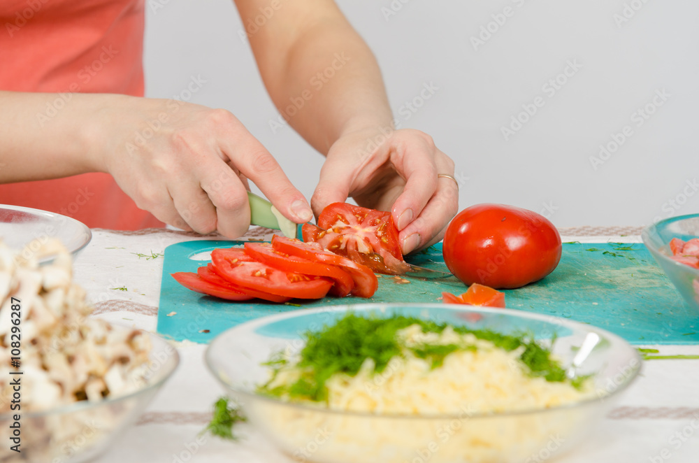 Close-up of female hands cutting tomato on kitchen table Close-up of female hands cutting tomato on kitchen table