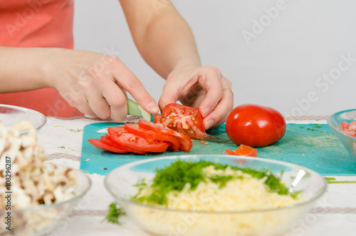 Close-up of female hands cutting tomato on kitchen table