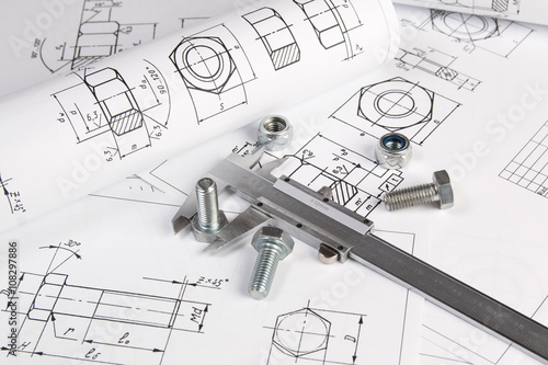 Caliper, bolts and nuts on a background of engineering drawings. Science, mechanics and mechanical engineering.