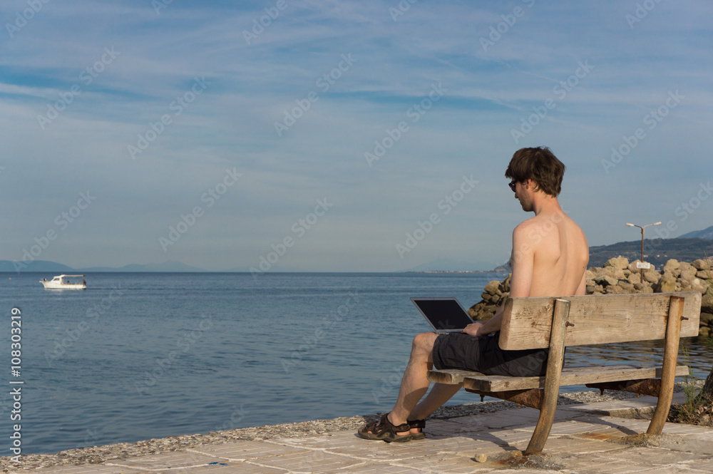 Young man working remotely near the sea