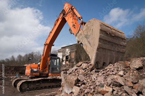 Mechanical digger, excavator with bucket in rubble on a clearance industrial site