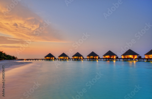 Water villas on Maldives resort island in sunset