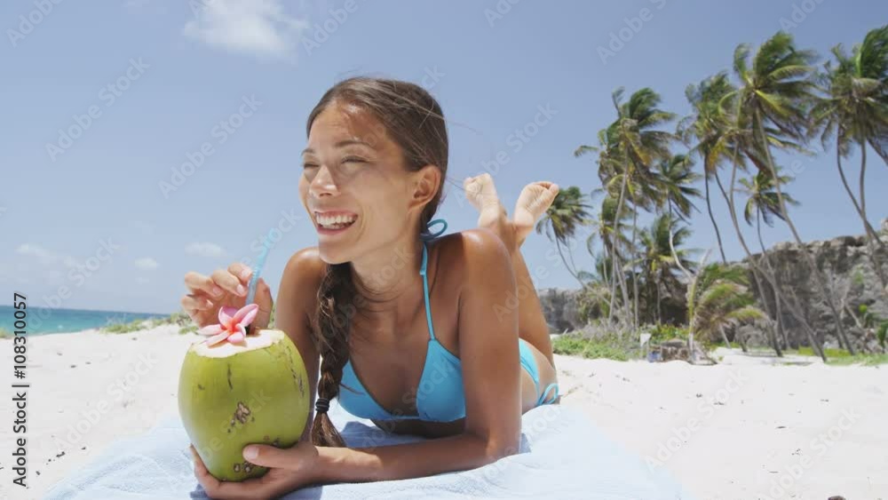 Happy beach bikini woman relaxing drinking fresh coconut water lying