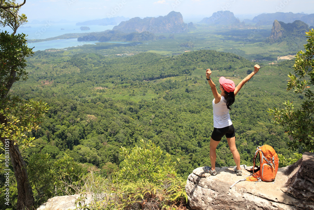 Naklejka premium cheering successful woman hiker open arms at mountain peak