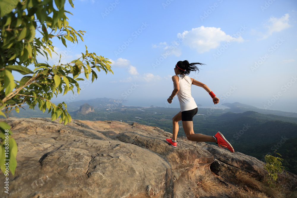 young asian woman runner running on mountain peak