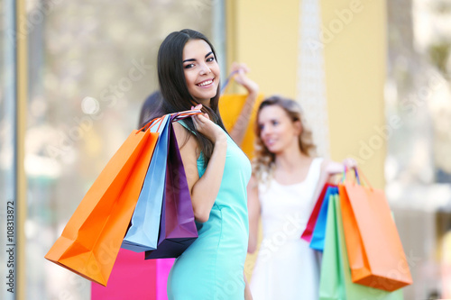 Beautiful young women with shopping bags on city street