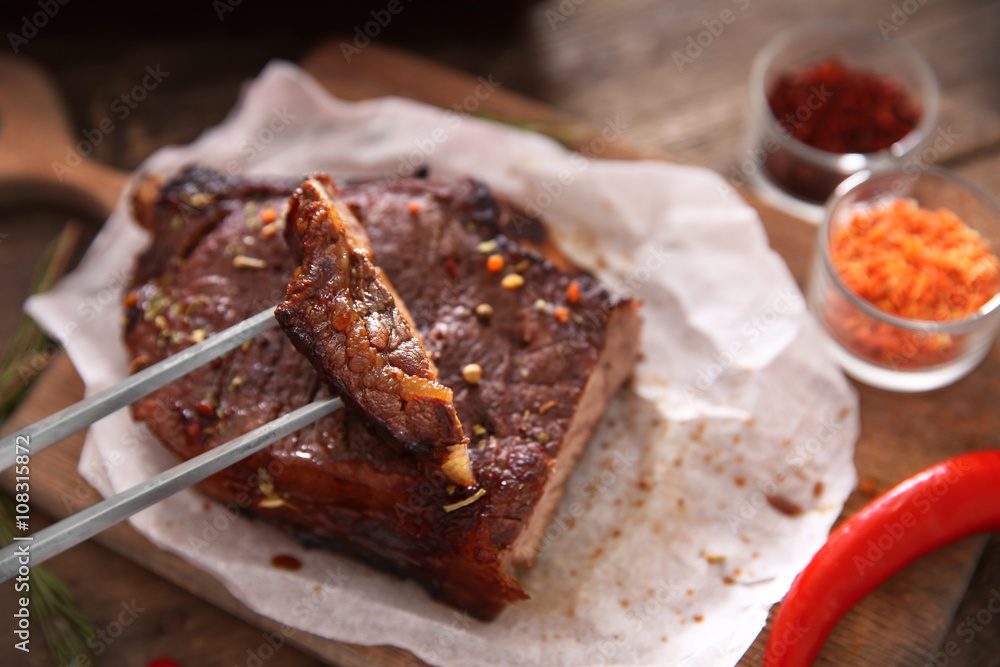 Sliced roasted pork steak with meat fork and spices on wooden background Sliced roasted pork steak with meat fork and spices on wooden background