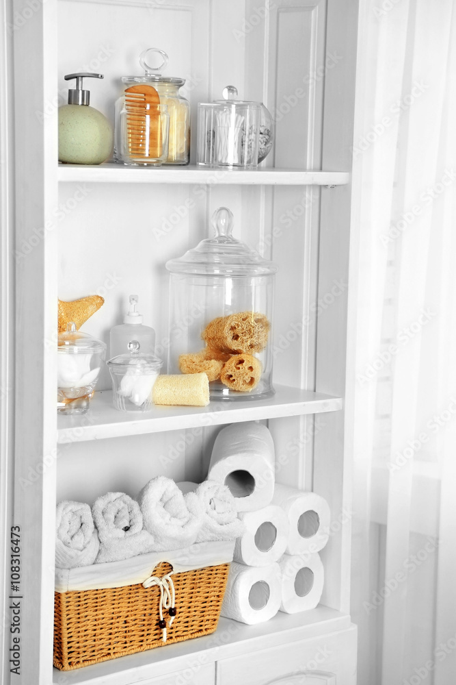 Bathroom set with towels, sponges and dispensers on a shelf in light interior Bathroom set with towels, sponges and dispensers on a shelf in light interior