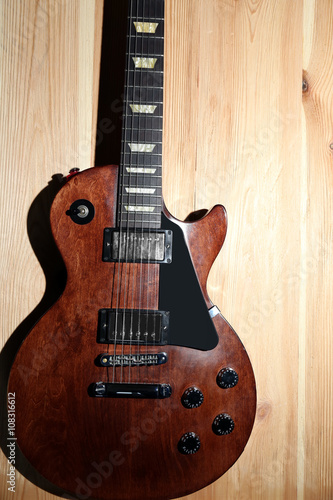 Brown electric guitar on wooden background