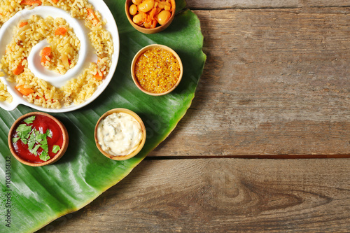 Fried rice with spices on banana leaf over wooden background