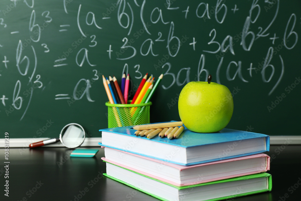 School books on desk near chalkboard School books on desk near chalkboard