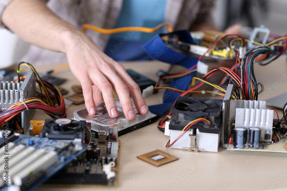 Naklejka premium Young man repairing computer hardware in service center