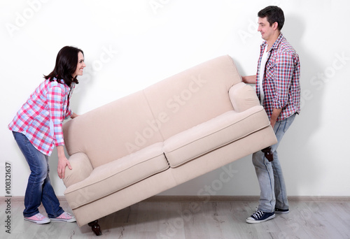 Young couple carrying sofa ...