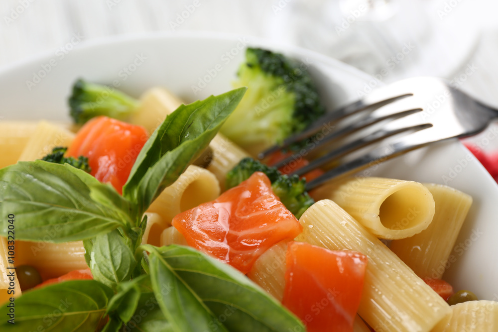 Plate of pasta with salmon and broccoli on table closeup Plate of pasta with salmon and broccoli on table closeup