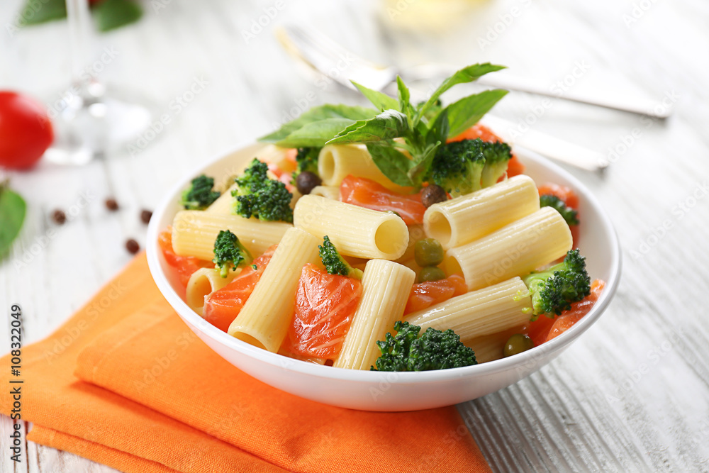 Plate of pasta with salmon and broccoli on table closeup Plate of pasta with salmon and broccoli on table closeup