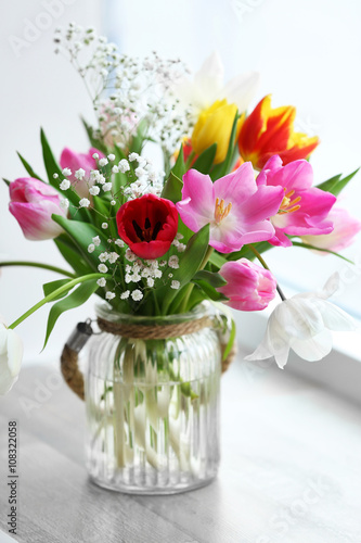 Bouquet of beautiful colorful tulips in glass vase on windowsill, indoors