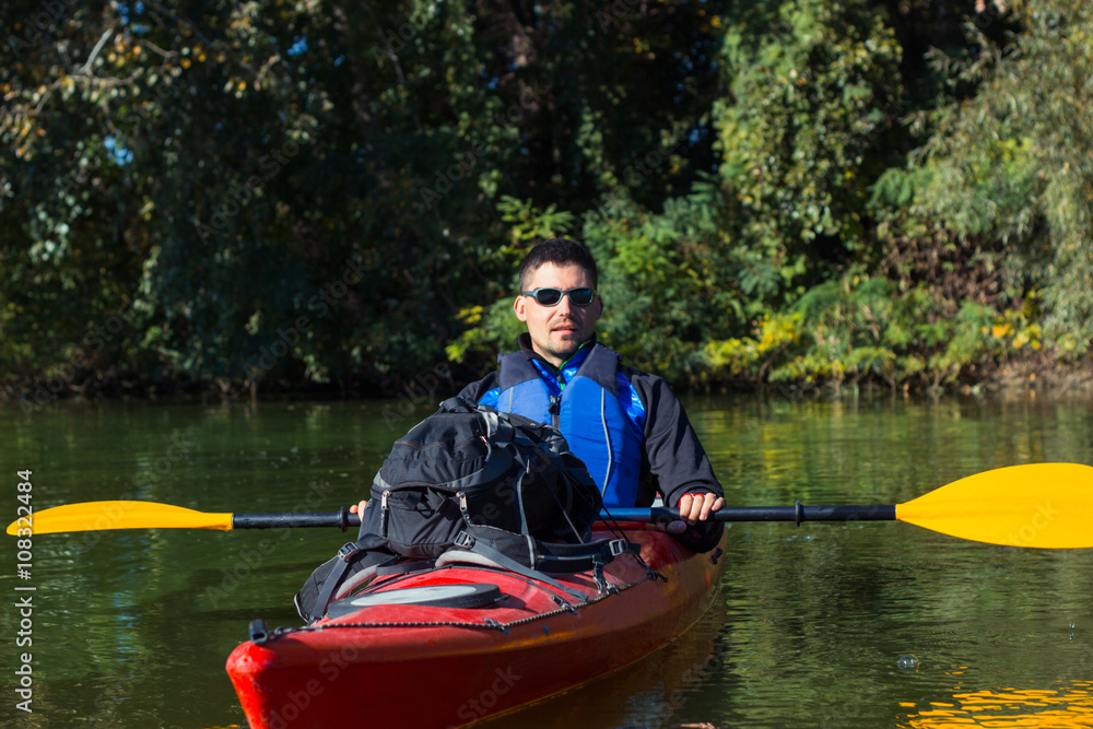 The man is kayaking on the river.