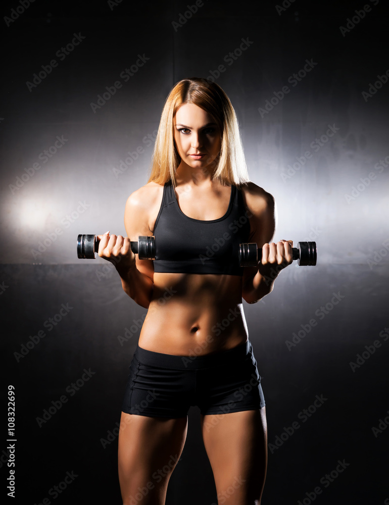 Athletic, fit and sporty girl training with dumbbells