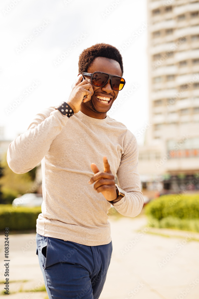 Handsome young man talking on the phone by texting and call in the street on sunny summer day

