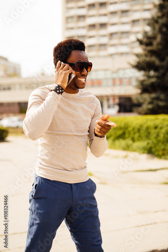 Handsome young man talking on the phone by texting and call in the street on sunny summer day 