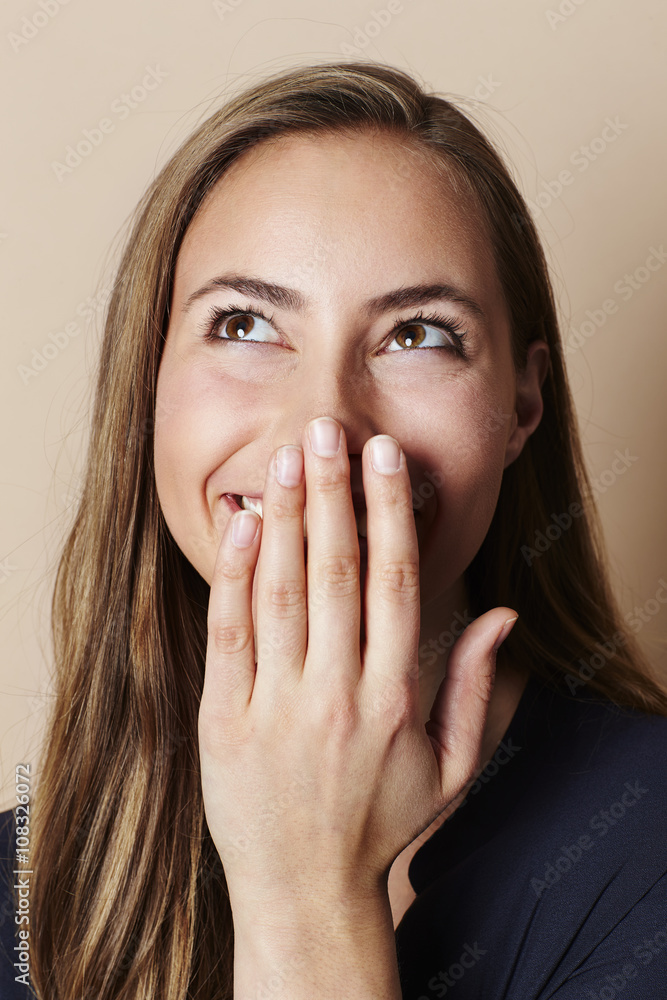 Sniggering girl with hand over mouth in studio Sniggering girl with hand over mouth in studio