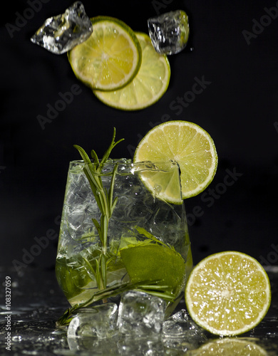 Gin and tonic cocktail with lime over black background.