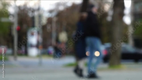 Unfocused blurred intersection with pedestrian walkway. People walking, bicyclists and inline skaters passing by, traffic light changing colors. photo