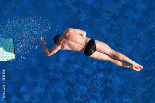 Sport diving from springboard. Male diver spinning in a difficult dive