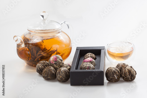 exotic green tea with flowers in glass teapot and cup isolated on studio background