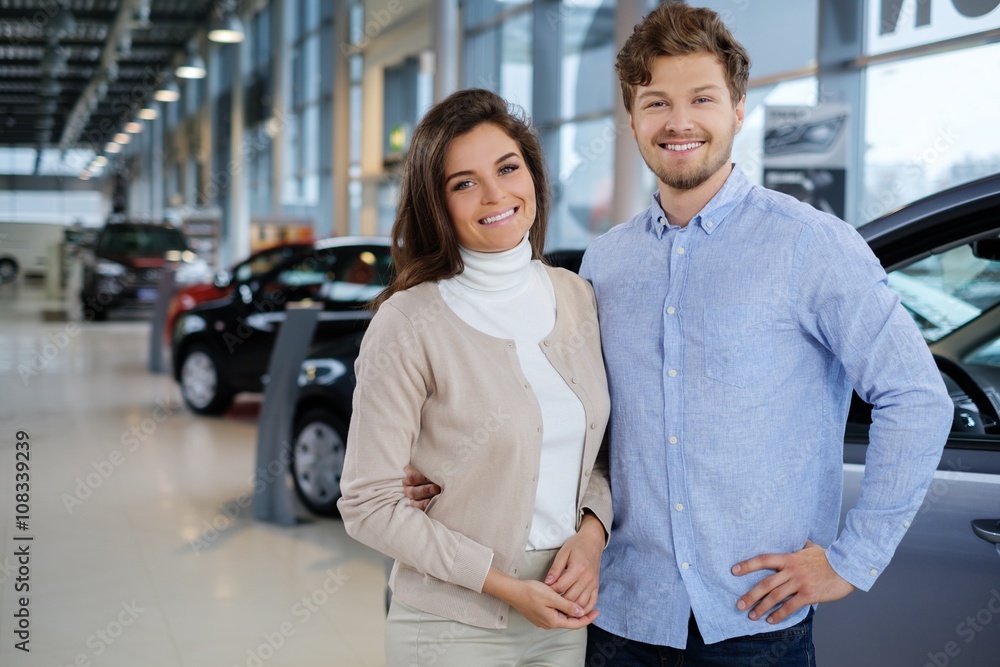 Beautiful young couple looking a new car at the dealership showroom. Beautiful young couple looking a new car at the dealership showroom.