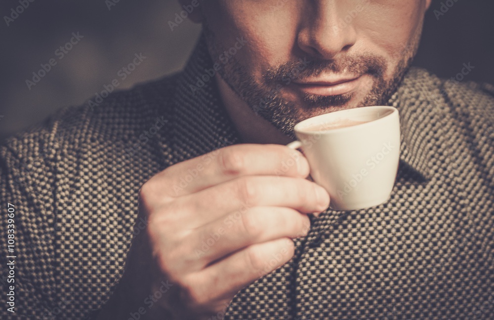 Confident well-groomed bearded man with cup of coffee on dark background. Confident well-groomed bearded man with cup of coffee on dark background.