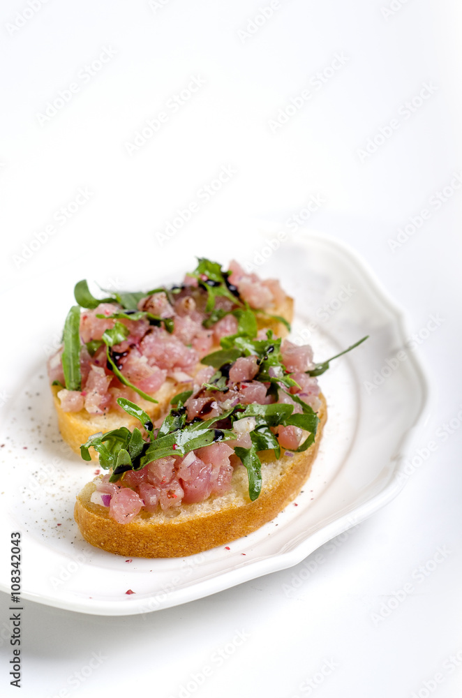 tasty bruschetta with tuna served on white plate