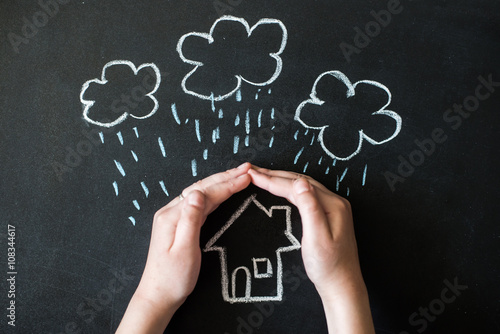 hands protects a house from the elements - rain or storm