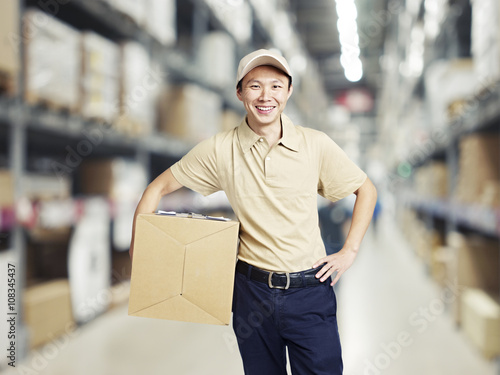 portrait of a young warehouse worker carrying a carton box