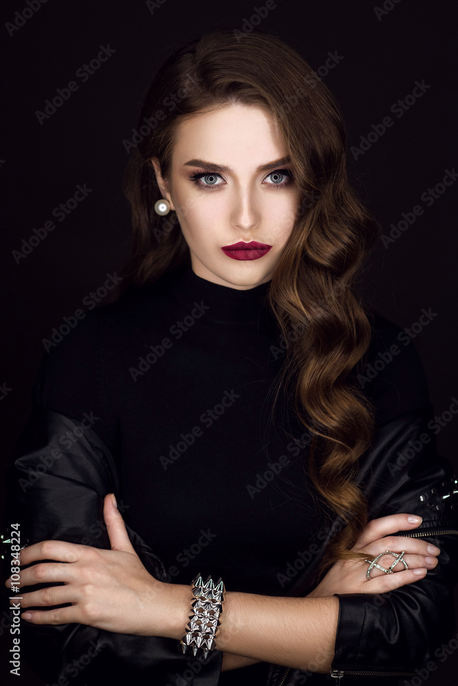Obraz premium Glamorous young beautiful rock style girl in black leather jacket with accessories on dark gray background