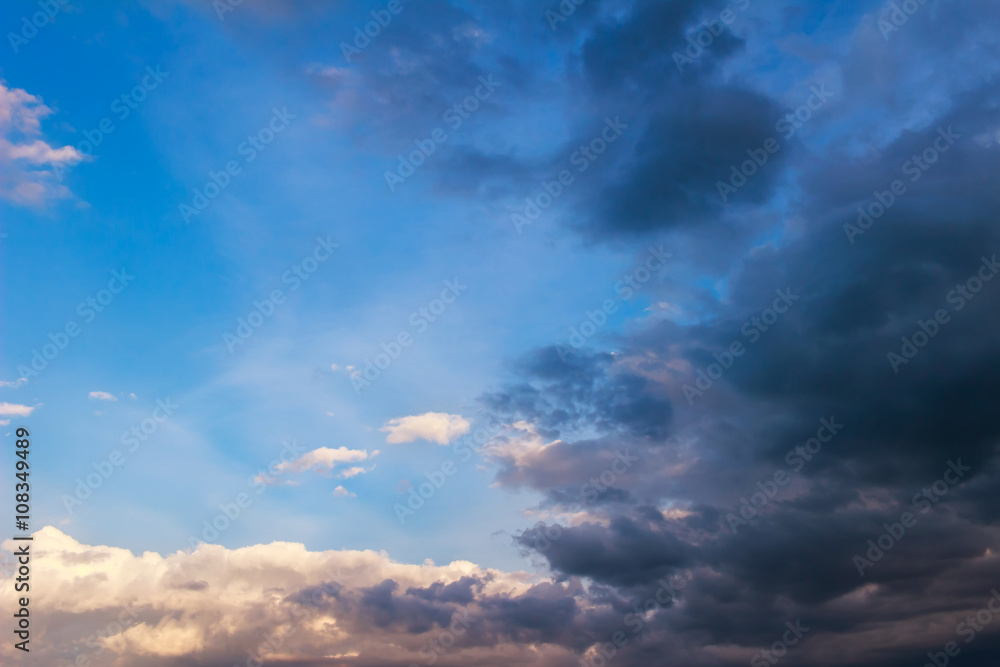 Obraz premium Blue sky background with small white, huge dark rain clouds.