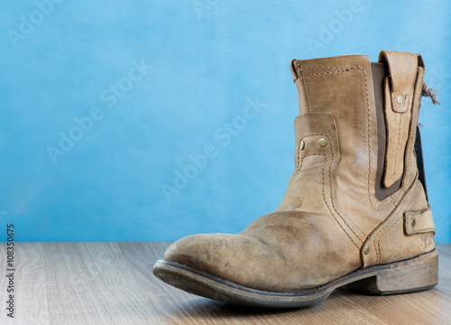 Patina Engineer Leather Boot on wooden surface and blue backgrou