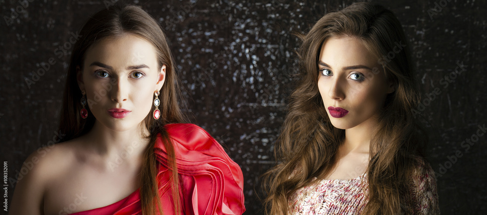 Two Young brunette women on dark studio wall background Two Young brunette women on dark studio wall background