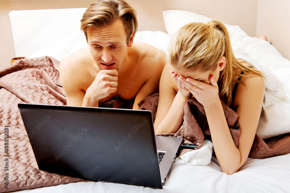 Obraz premium Young couple using laptop in bed