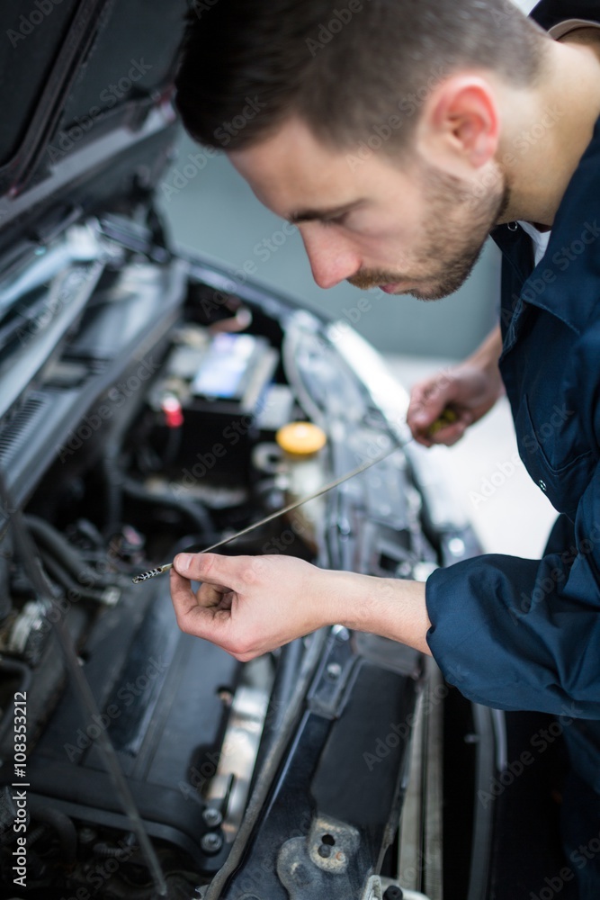 Mechanic checking the oil level in a car engine Mechanic checking the oil level in a car engine