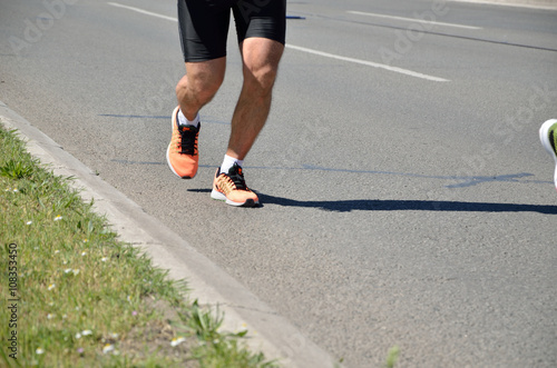 Motion blurred legs of runner in the street race (marathon) in sports gear.
