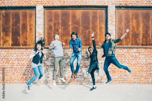 Group of young beautiful multiethnic man and woman friends having fun jumping outdoor in the city - happiness, friendship, teamwork concept