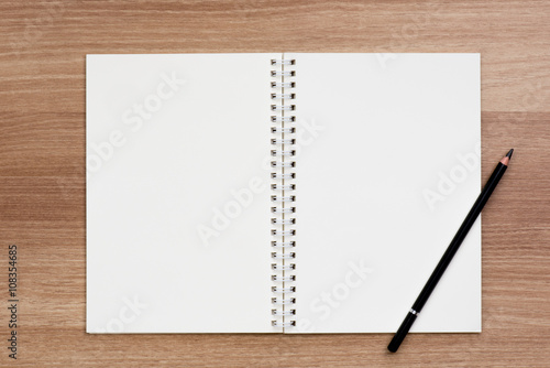 Opened blank ring spiral binding notebook with a pencil on wooden surface